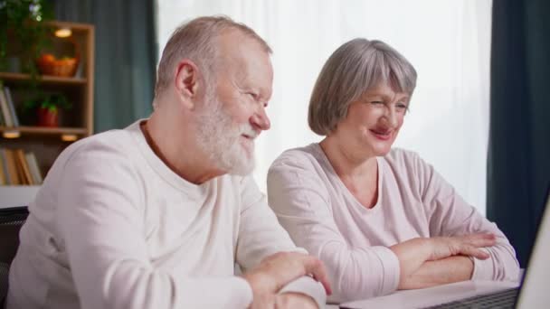 online bellen, gelukkige oudere ouders praten met hun volwassen kinderen via videoconferentie op laptop terwijl ze in de kamer aan tafel zitten - Video