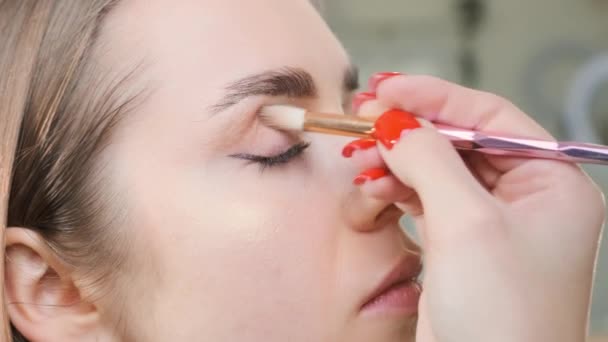 Skilled woman softly blends outer edges of eyeshadow. Professional artist ensures look uniquely suited to lady client personal style - Footage, Video