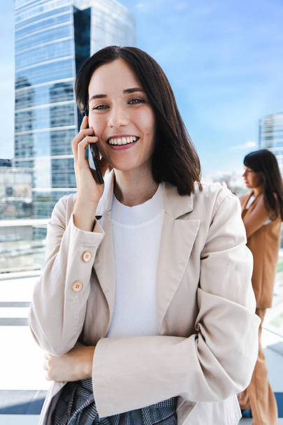 A woman is talking on her cell phone. She is smiling and she is in a good mood - Photo, image