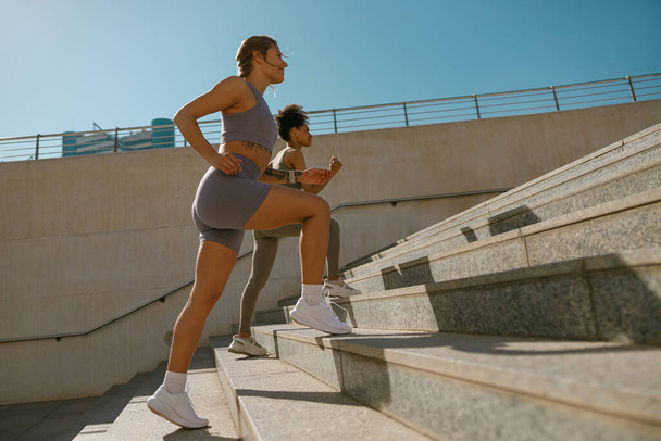 Vue latérale des femmes sportives en vêtements de sport font du jogging dans la ville le matin. Atteindre le but - Photo, image