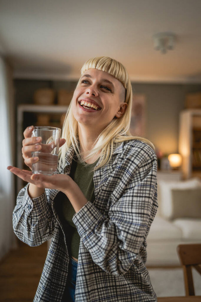jedna kobieta piękna blondynka młody dorosły kobieta nowoczesna fryzura w domu ze szklanką wody - Zdjęcie, obraz