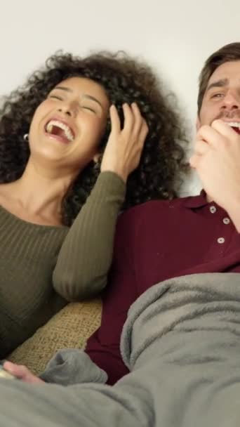 Zeitlupenvideo eines multirassischen Paares, das lacht, während es sich zu Hause einen lustigen Film ansieht - Filmmaterial, Video