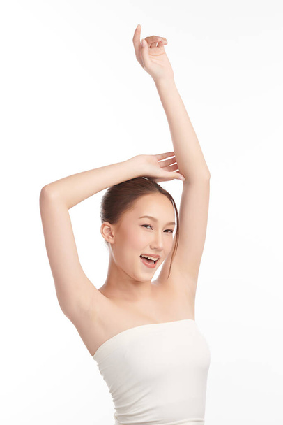 Kaunis nuori aasialainen nainen nostaa kädet ylös keuliminen puhdas ja hygieeninen kainaloissa tai kainaloissa valkoisella pohjalla, sileä kainalon puhtaus ja suoja käsite - Valokuva, kuva