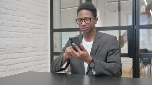 Молодий африканський чоловік шокований втратами по телефону в офісі - Кадри, відео