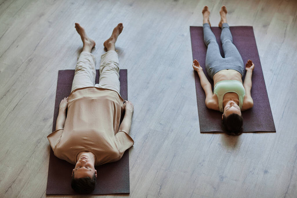 Vista superior a dos jóvenes acostados en el suelo en meditación con los ojos cerrados, espacio para copiar - Foto, Imagen
