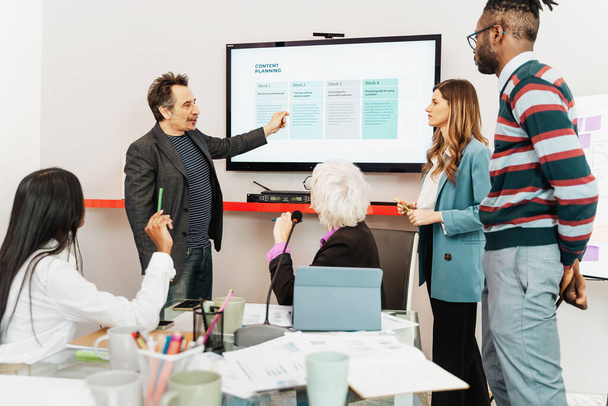 コンテンツプランニングセッションに従事するビジネスチーム - スクリーン上の戦略を概説するプレゼンター, コンテンツ開発 - マーケティングチームの相互作用, 創造的なブレインストーミングのためのワークショップ. - 写真・画像
