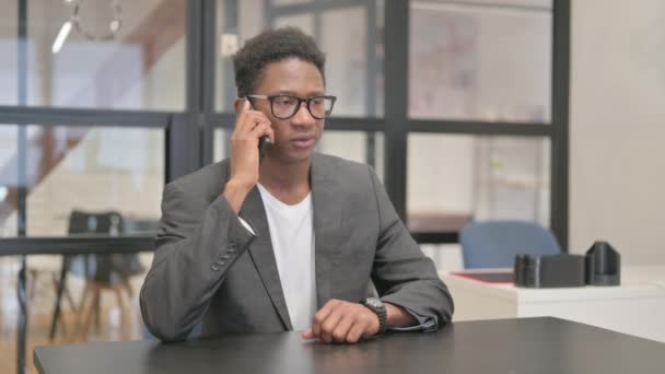 Uomo afroamericano che parla al telefono in ufficio - Filmati, video
