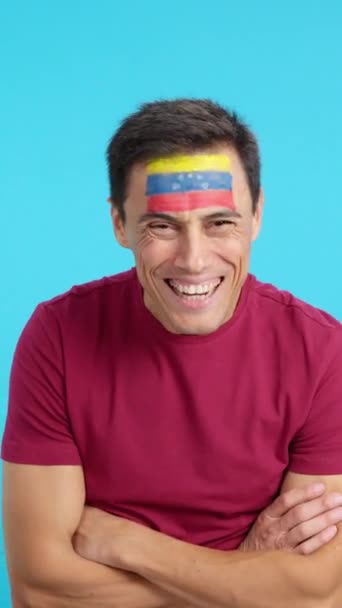 Video in studio with chroma of a man standing with venezuelan flag painted on face smiling with arms crossed - Footage, Video