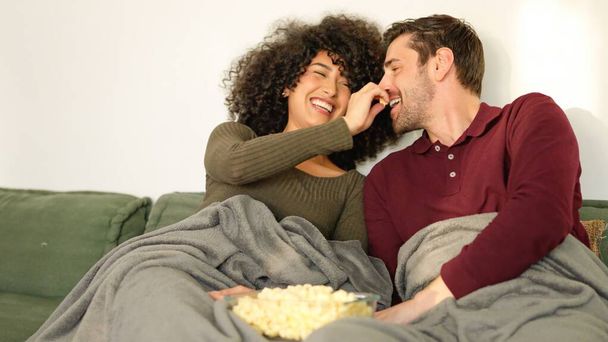 Kobieta wkłada popcorn do ust swoich chłopaków podczas oglądania filmu w domu - Zdjęcie, obraz