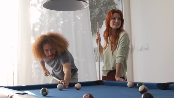 Multiethnic diverse male and female friends in casual clothes talking while playing pool in game room during weekend day at home - Footage, Video
