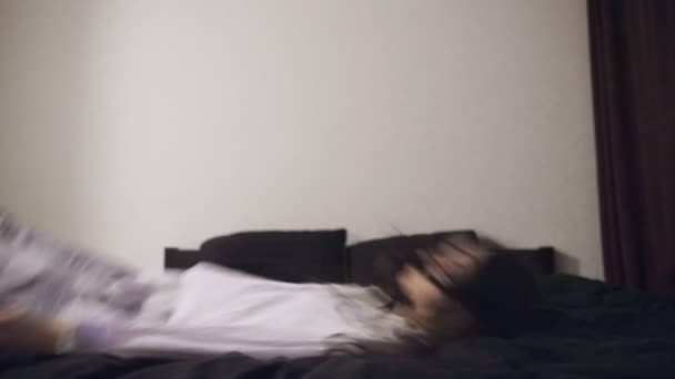 Mujer joven cayendo en la cama, arrojando el cuerpo en el colchón en casa. En cámara lenta. Concepto de estilo de vida - Imágenes, Vídeo