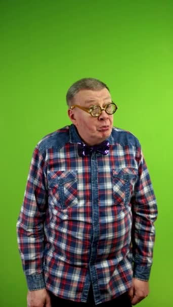 Strange man in funny glasses puts fingers to lips and says shhh demanding silence. Amusing mature man demanding shut up and waving his finger in negative. Green screen. Chroma key. Vertical. - Footage, Video