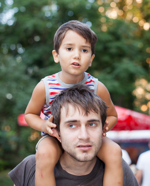 Дитина сидить на шиї свого батька
 - Фото, зображення