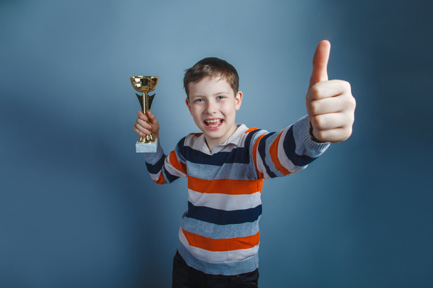European-looking boy of ten years holding a cup award thumbs up - 写真・画像