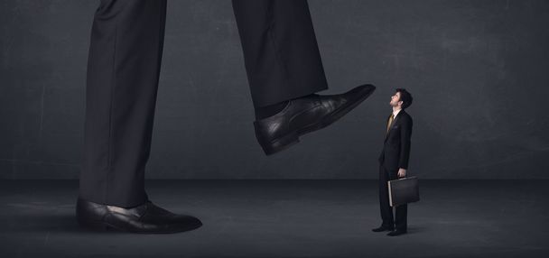 Giant person stepping on a little businessman concept - Foto, Imagen