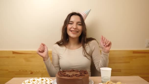 Masanın önünde elinde şenlikli bir pastayla oturan bir kız. 17 numaralı pastaya mum takılmış. Doğum günü kutlaması konsepti. - Video, Çekim