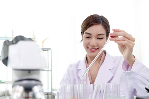 Portret van een prachtige Aziatische vrouwelijke wetenschapper in laboratoriumjassen die wetenschappelijke experimenten doet, gelukkige onderzoeker die laboratoriumapparatuur gebruikt voor onderzoek, vrouw die werkt in wetenschap en bio-medisch veld concept. - Foto, afbeelding