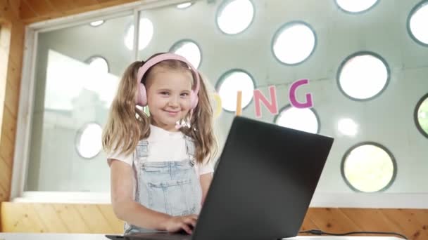 Jonge student glimlachend en kijkend naar de camera terwijl hij aan de laptop werkt. Schoolmeisje wonen creatieve online klaslokaal. Aantrekkelijke blanke gelukkige jongen met behulp van slimme technologie. Creatief leren. Erutie. - Video