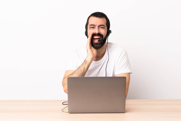 Télévendeur caucasien homme travaillant avec un casque et avec ordinateur portable criant avec bouche grande ouverte. - Photo, image