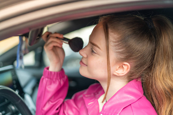 Junge hübsche Mädchen in einem Auto mit Make-up-Pinsel - Foto, Bild