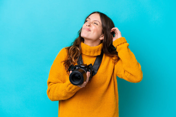 Jeune photographe femme isolée sur fond bleu ayant des doutes et avec une expression du visage confuse - Photo, image