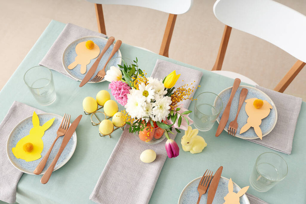 Schöne Tischdekoration für Ostern dekoriert mit einem Strauß Möhren und Blumen im Speisesaal - Foto, Bild