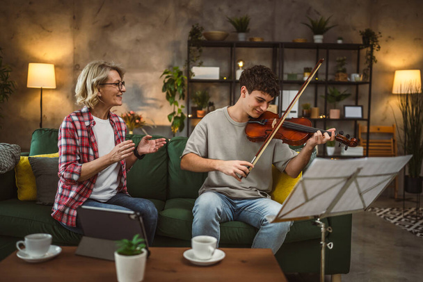 Giovane uomo imparare a suonare il violino sotto istruzione della donna matura insegnante tutor femminile a casa prendere classe privata - Foto, immagini