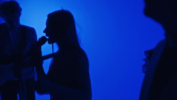 Profesyonel stüdyoda mavi filtreli müzik yapan kadın şarkıcı ve müzisyenlerin yan görüntüleri. - Video, Çekim