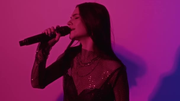 Estrarre filmati di cantante femminile che esegue canzone insieme a dondolo bassista mentre gigging in rosa neon illuminato studio - Filmati, video