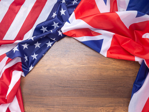 Bandera americana y británica como fondo sobre mesa de madera con espacio de copia para texto. Vista superior. Relaciones internacionales. - Foto, imagen
