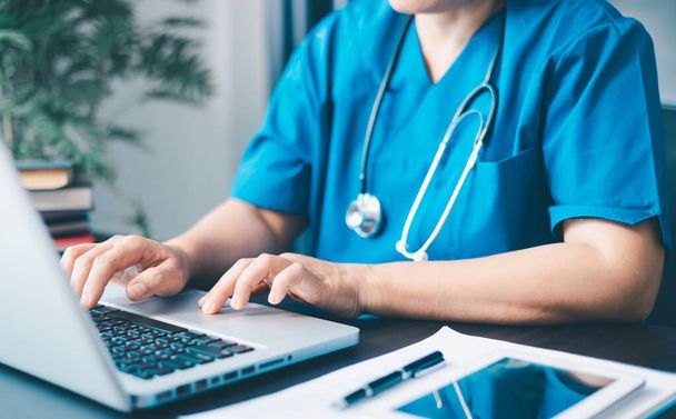 Kobieta lekarz za pomocą komputera laptopa do zarządzania pracownikami, przepływ pracy w szpitalu i rozwiązania dla personelu kliniki w oprogramowaniu lub aplikacji. w biurze. - Zdjęcie, obraz