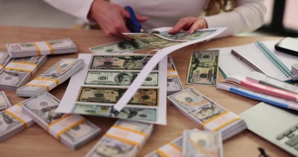 Nainen väärentäjä leikkaa väärennettyä rahaa saksilla pöydässä kaapissa. Väärennettyjen dollarien setelien valmistus maksua varten virassa hidastettuna - Materiaali, video