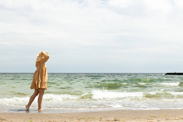 Una ragazza in abito cammina sulla spiaggia in estate. - Foto, immagini