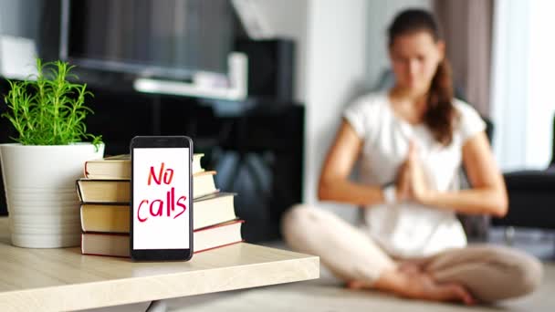 Digital detox concept. In the foreground is a smartphone with the text No Calls and woman meditating in the background. High quality 4k footage - Footage, Video