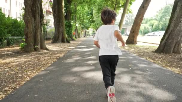 小児の自由 - 若い男の子は葉っぱの郊外の歩道に沿ってダッシュします - 映像、動画