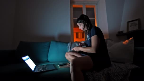 Midden in de nacht - Vrouw verzamelt documenten voor onderzoek met behulp van laptop in donkere appartement - Video