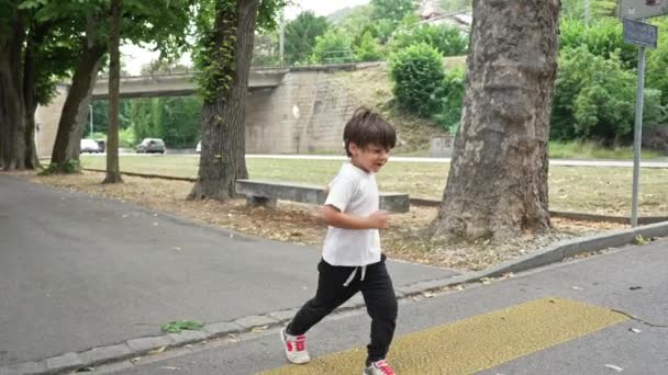Glückliches Kind hüpft über Fußgängerweg - Kind überquert Straße auf Fußgängerüberweg im Stadtbummel - Filmmaterial, Video
