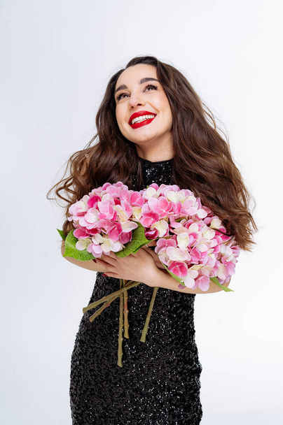 Beautiful brunette girl with bouquet of flowers in her hands - Fotó, kép