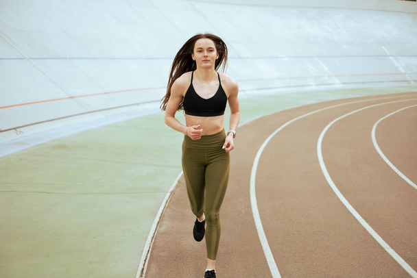 Atletisch meisje hardlopen en training in het stadion. - Foto, afbeelding