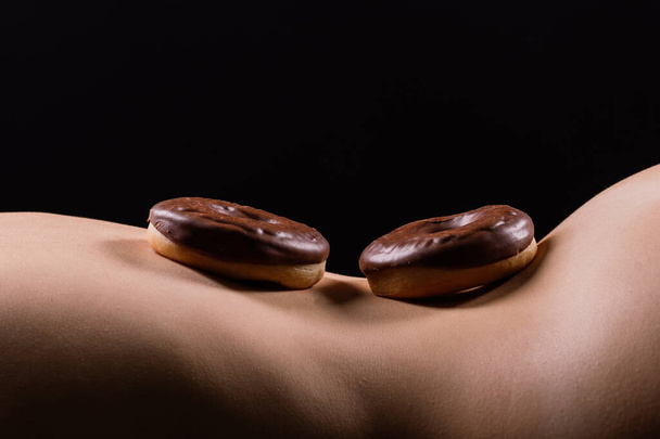 Close up shot of nude womans body with chocolate covered donuts - Foto, Bild