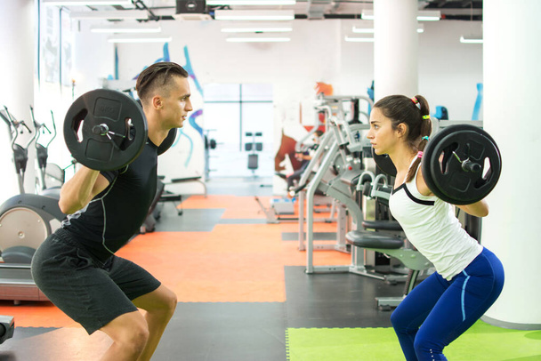 Férfi személyi edző súlyok emelés képzés női ügyfél egy edzőteremben. - Fotó, kép
