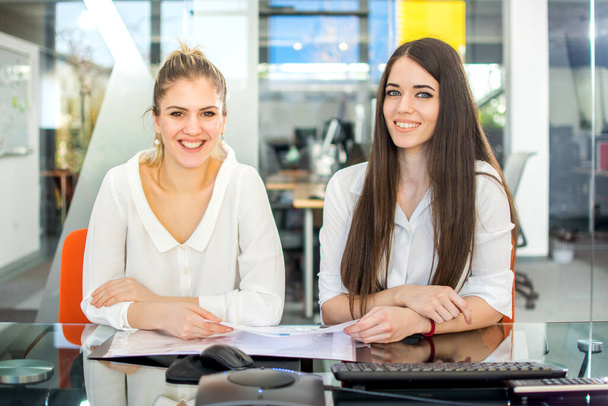 Deux femmes d'affaires souriantes assises dans le bureau et regardant la caméra. - Photo, image