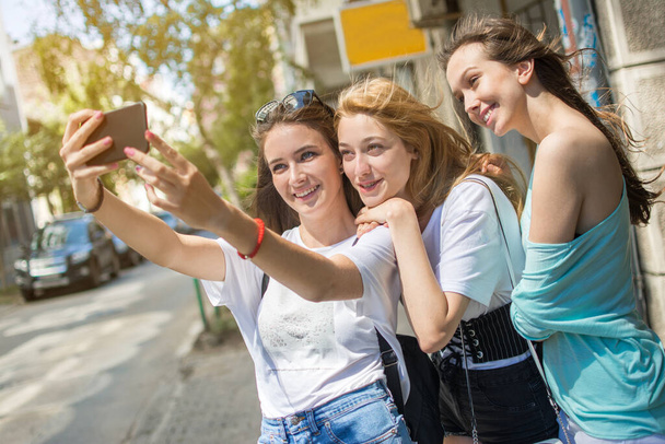 Mosolygó tinédzser lányok egy szelfi fotó a szabadban - Fotó, kép