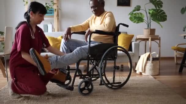Soins compatissants à la maison avec une infirmière aidant un aîné en fauteuil roulant, période de récupération. - Séquence, vidéo
