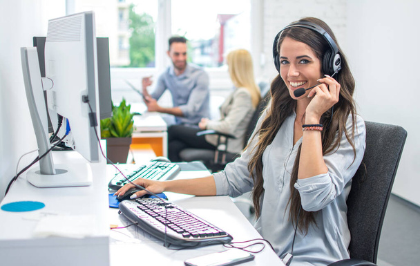 Portrait of happy smiling female customer support phone operator at workplace - Photo, Image