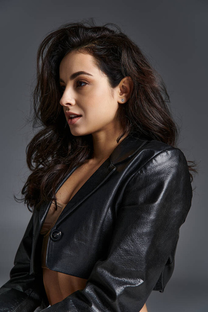 Stylish young woman strikes a confident pose in a black leather jacket. - Photo, Image
