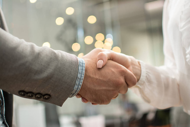 Close up de empresária e empresário apertando as mãos após uma reunião de negócios no escritório. - Foto, Imagem