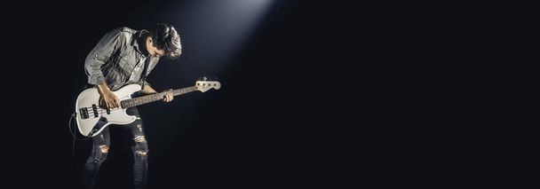 Ένας αρσενικός κιθαρίστας παίζει ηλεκτρική κιθάρα σε σκοτεινό φόντο σκηνής. Web, κοινωνικό πρότυπο banner μέσων μαζικής ενημέρωσης. Αντιγραφή χώρου. - Φωτογραφία, εικόνα