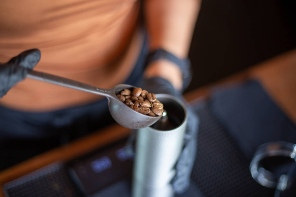 Kahve makinesinin kaşığında seçici odak noktası kavrulmuş kahve çekirdekleri kokulu kahverengi kahve çekirdeklerini kepçelemek için bir kaşık kullanın.. - Fotoğraf, Görsel