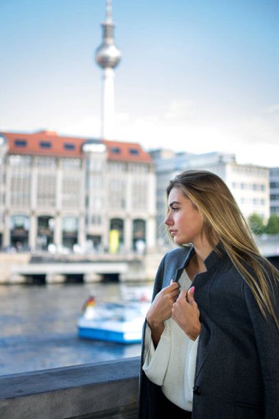 Fiatal nő kabátban élvezi a kilátást a Spree folyón Berlinben. - Fotó, kép